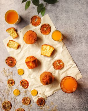 Portakallı kekler, portakal suyu ve portakal dilimlerinin masa üstü fotoğrafı.