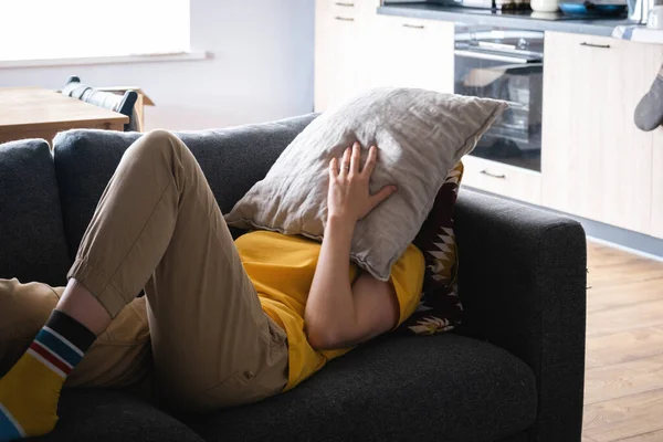 Mujer joven desconocida acostada en el sofá cansada con almohada en la cabeza. Imagen de archivo