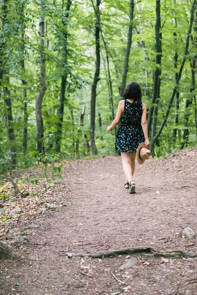 穿着衣服头戴米黄色帽子的年轻千禧年女子快乐而轻松地站在森林里，享受大自然与宁静。单独旅行概念. — 图库照片