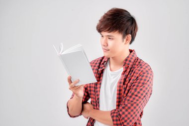 Genç Asyalı bir adam kitap okuyor, gülümsüyor.