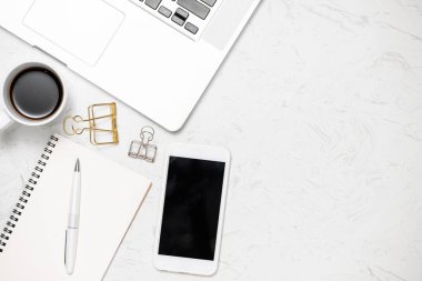 Beyaz klavye faresinin iş yerindeki en iyi görüntüsü beyaz masa üzerinde bulunan kahve tutacağı ve kalem dolu spiral defter kapağı.