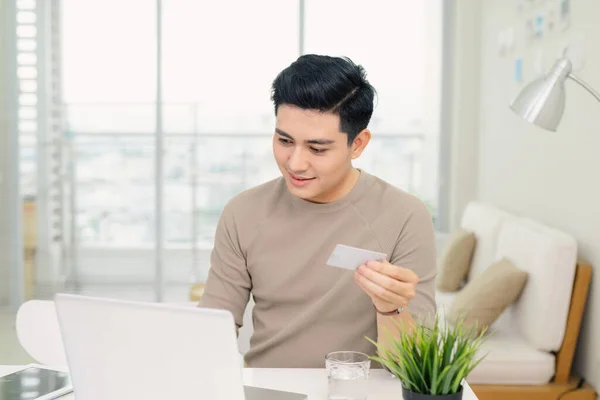 Bonito Jovem Empresário Usando Computador Enquanto Segurando Cartão Crédito Escritório — Fotografia de Stock