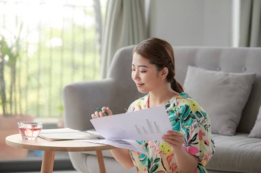 Elinde kağıt olan bir kadın, evde çalışıyor.