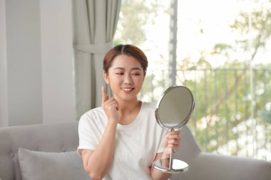 Güzel, mutlu, genç ve sağlıklı bir kadın aynaya bakıyor.