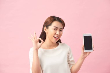 Mutlu bir Asyalı portresi. Güzel, güzel bir kadın. Elinde cep telefonu ve el kol işareti var.