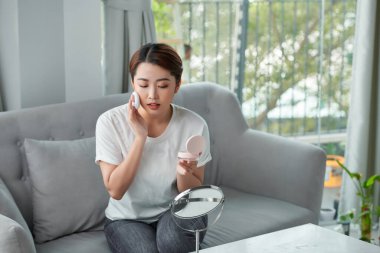 Mutlu genç bir kadın aynaya bakarken kızarıyor.