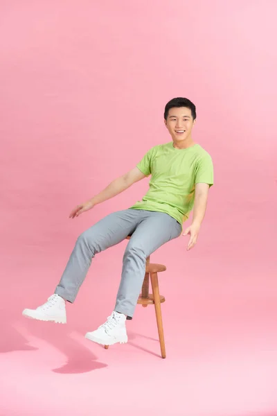 Τύπος Μπλουζάκι Κάθεται Μια Καρέκλα Μπροστά Από Ένα Ροζ Τοίχο — Φωτογραφία Αρχείου