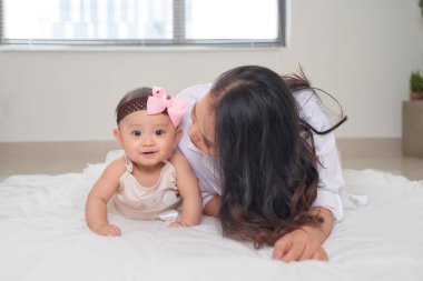 Yatak odasında bebeğiyle gülümseyen güzel bir annenin portresi.