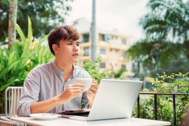 Genç adam dışarıda çalışmak için dizüstü bilgisayar kullanıyor.