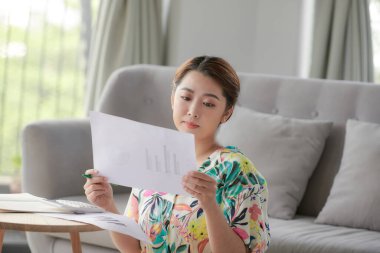 Elinde kağıt olan bir kadın, evde çalışıyor.