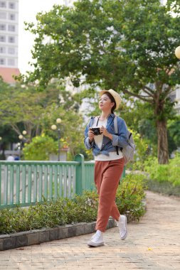 Güneşli bir günde sokakta poz veren neşeli, genç bir hippi kız.