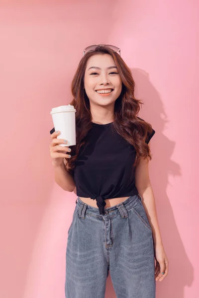 テイクアウトコーヒーを保持している女性の写真はピンクの壁の上に立つ — ストック写真