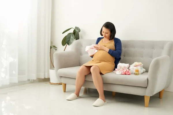 Schwangere Entdeckt Babykleidung Auf Sofa — Stockfoto