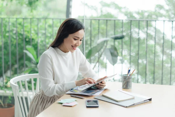 デジタル タブレットを使用オンラインして近代的なオフィスに彼女の机に一人で座って笑顔魅力的な若い実業家 — ストック写真
