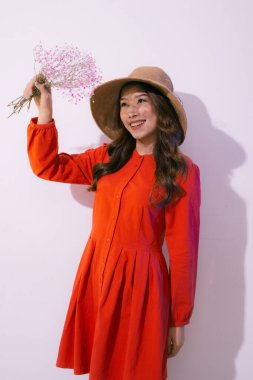 Hasır şapkalı ve pembe çiçekli kırmızı elbiseli genç bir kadın.