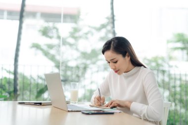 Genç bir kız öğrenci masada oturan, eğitim sırasında dizüstü bilgisayar kullanarak.