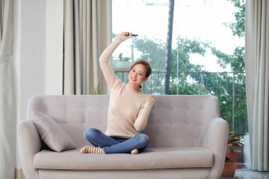  Emotional woman enjoying football game holding remote control