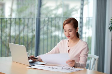 side view of smiling asian female freelancer working at home
