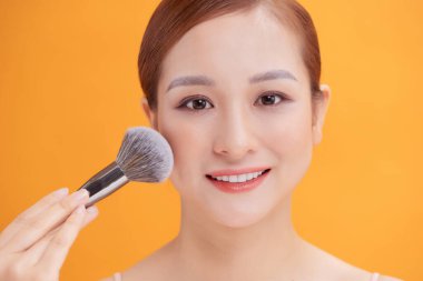 Utangaç fırçalı çekici bir makyajcı kadın. Kozmetik ürünleri