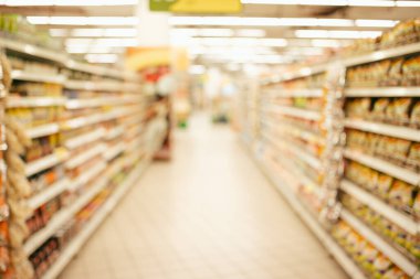 Renkli rafları ve tanınmayan müşterileri olan soyut bulanık süpermarket koridoru