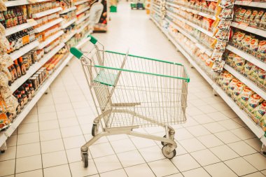 Boş yeşil alışveriş arabasıyla süpermarket koridoru.