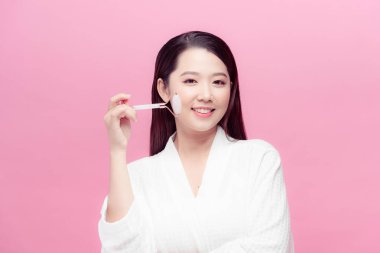 Güzel yüzünü kozmetik aletlerle önemseyen bir kadın. Deri bakımı konsepti. Kız makyaj malzemesi tutuyor.