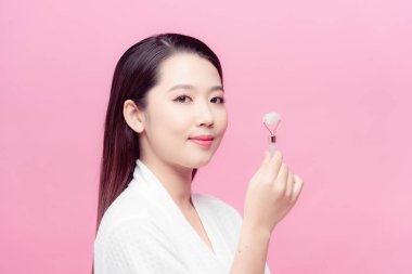 Güzel model yüz masajı için kozmetik taş silindiri kullanıyor..