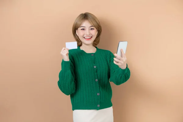 Mujer Joven Sonriente Sosteniendo Teléfono Móvil Mostrando Tarjeta Crédito Aislada —  Fotos de Stock