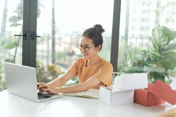 Young woman uses a laptop to chat with customers who come to order product