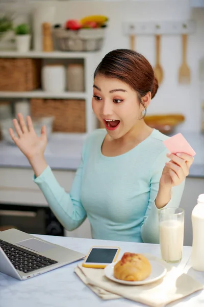 woman full of energy and optimism looking at her laptop with credit card in her hand