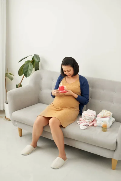 Schöne Junge Schwangere Frau Mit Babykleidung Hause — Stockfoto