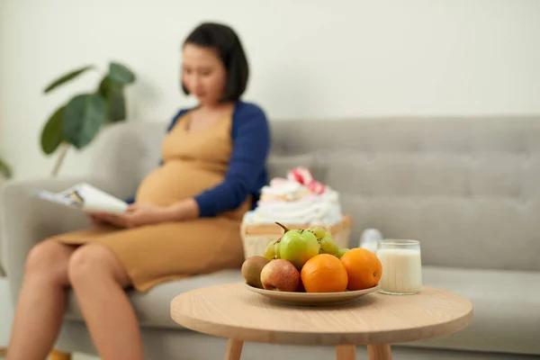 Junge Schwangere Frau Sitzt Auf Sofa Mit Milch Und Früchten — Stockfoto