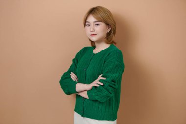 Çekici, kendine güvenen bir patronun fotoğrafı. Bej arka planda elleri bağlı bir iş kadını.