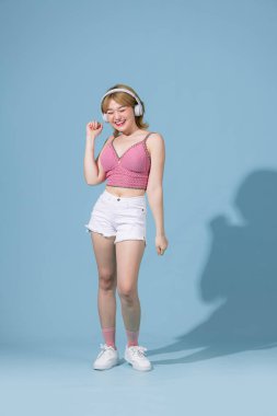 Full length body size view of a pretty cheerful girl listening song having fun dancing chill isolated on blue pastel background