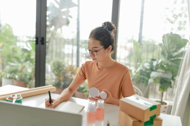  Serbest çalışan kadın satıcı dükkanda ambalaj işlemi için ürün hazırlar.