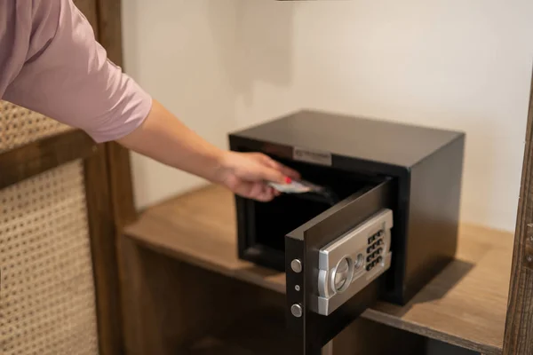 Hand putting password in the safety money box in hotel room