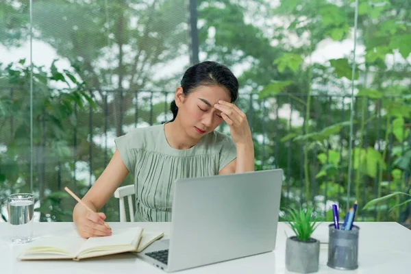 Shot of stressed business woman working from home on laptop looking worried, tired and overwhelmed.