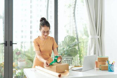 Serbest çalışan kadın satıcı dükkanda ambalaj işlemi için ürün hazırlar.