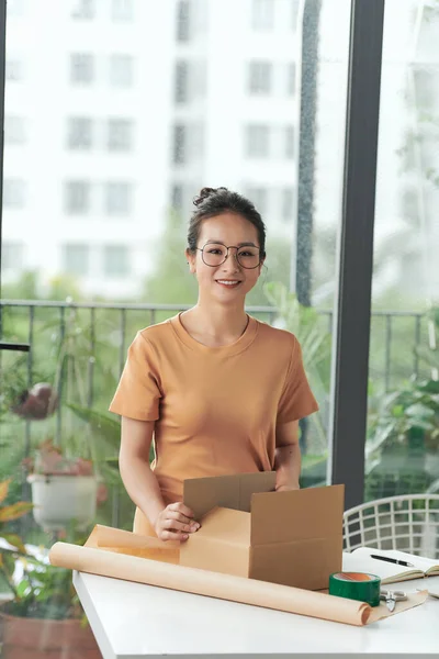 Female business owner smiling and feeling happy while preparing packages to ship to customers