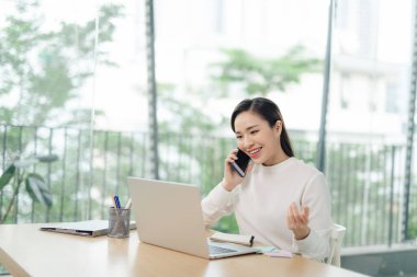Asian woman freelancer working in modern office, talking on phone,