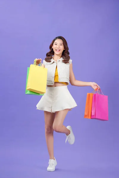 全长侧面照片 年轻姑娘开心的笑着提着包走出去 在紫色的背景下独立购物 — 图库照片