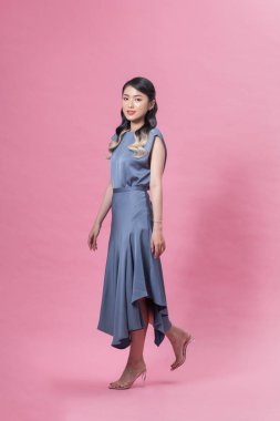 Pembe arka planda yürüyen ve gülümseyen güzel, genç bir manken. 