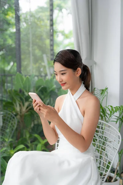 Ευτυχισμένη Νεαρή Ασιατική Κυρία Χρησιμοποιώντας Σύγχρονο Smartphone Ενώ Αναπαύεται Στο — Φωτογραφία Αρχείου