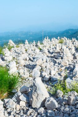 Turistler tarafından, Njegos mozolesi yakınlarındaki Jezerski Dağı 'nın tepesinde şans getirmesi için yapılmış taş taretler. Lovcen Ulusal Parkı. Karadağ. Yaz mavisi dağ manzarası.