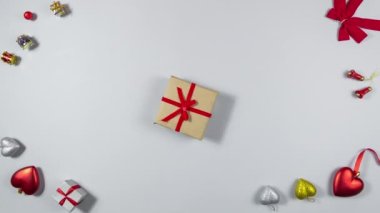 4k Brown hediye kutusu çerçevede kırmızı kurdeleyle bağlanmış, dönüyor ve yavaşça duruyor. Tatil ve hediye hazırlama kavramı. Açık gri arkaplan. Düz yatıyordu. Uzayı kopyala Hareketi durdur
