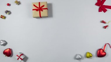 Kırmızı kurdeleli 4k hediye kutusu görünür, dinamik olarak farklı yönlere hareket eder, sonra eller onu yakalar. Tatil ve hediye kavramı. Açık gri arkaplan. Düz yatıyordu. Uzayı kopyala Hareketi durdur.