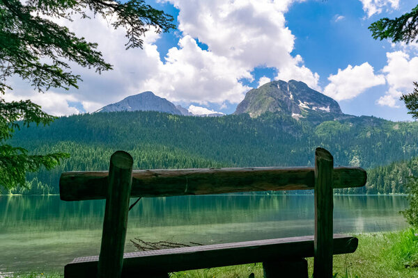 Wooden bench near Glacial Black Lake. Premium tourist attraction of Durmitor National Park. Walking path circles around lake, and is popular destination for recreation and hiking. Montenegro