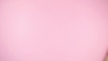 Hüner kağıdına sarılı ve kırmızı kurdeleyle bağlanmış 4K tatil hediyesi kutusu dinamik bir şekilde çapraz hareket ediyor. Merkezde boşluğu kopyala. Açık pembe arka plan. Düz yatıyordu. Uzayı kopyala Hareketi durdur.