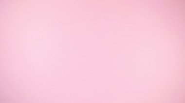 Hüner kağıdına sarılı ve kırmızı kurdele hareketleriyle bağlanmış 4K tatil hediyesi kutusu. Merkezde boşluğu kopyala. Açık pembe arka plan. Düz yatıyordu. Uzayı kopyala Hareketi durdur.