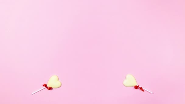4K两颗心形的白色巧克力糖果合并成一个大的 小的心出现又消失了 情人节的概念 平躺在床上复制空间 停止动作动画 浅粉色背景 — 图库视频影像